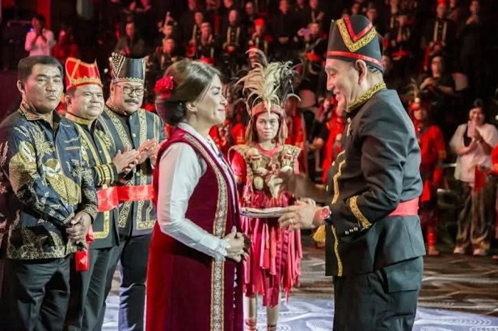 Angelica Tengker menerima Pataka KKK dari Theo L. Sambuaga, simbol sah kepemimpinan budaya dan harmoni baru diaspora Minahasa. (Instagram.com @vidiwowor)